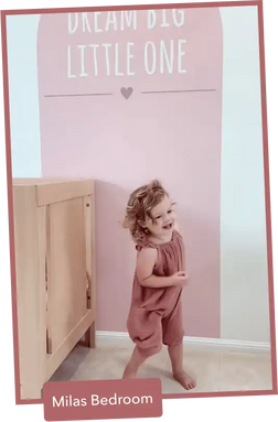 A child wearing a dusty rose-colored romper.