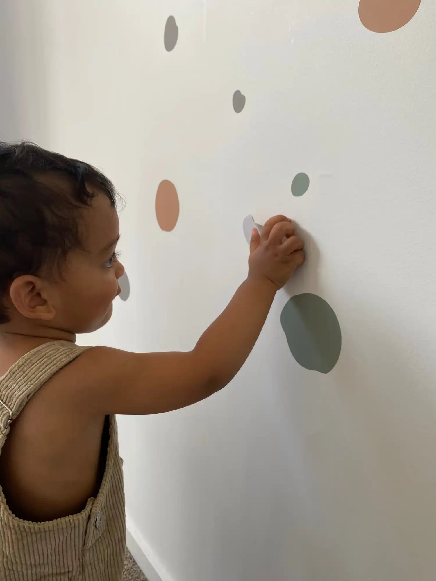 A child drawing or placing polka dots on a wall.